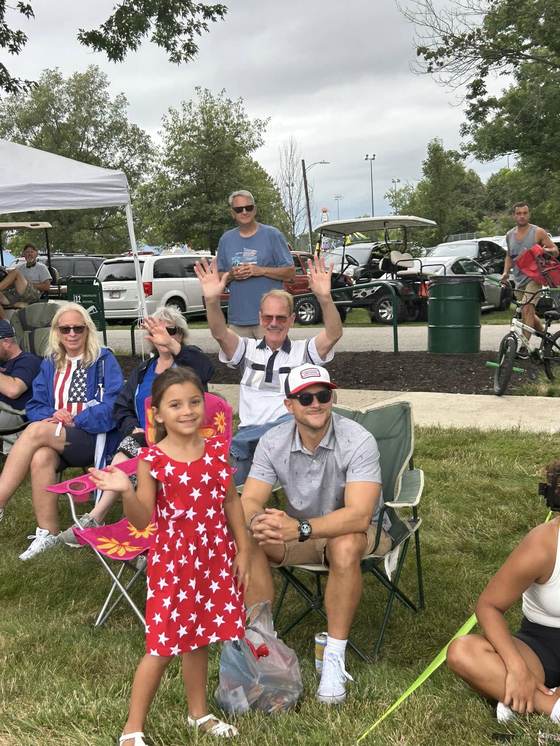 Family waving from the lawn at the parade